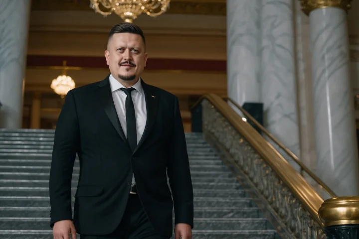 Евгений Зайферт в чёрном вечернем костюме спускается по мраморной лестнице оперного театра